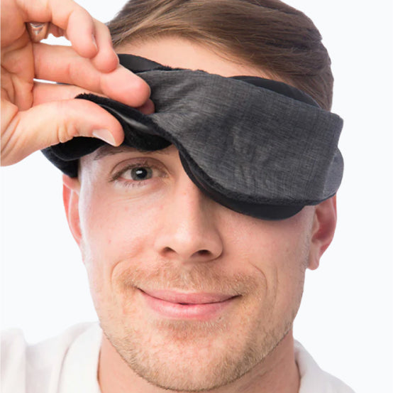 man wearing a sleep mask, lifting up one side